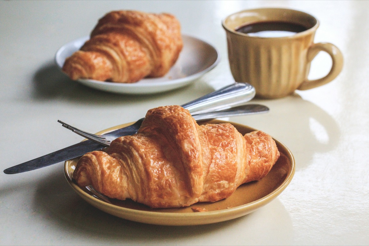 Nygräddade croissanter på fat med en kopp kaffe i dagsljus — Kafé Norr